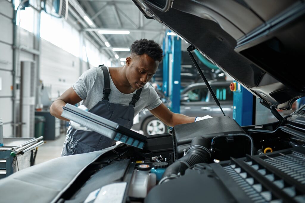 Male worker changes oil in engine, car service