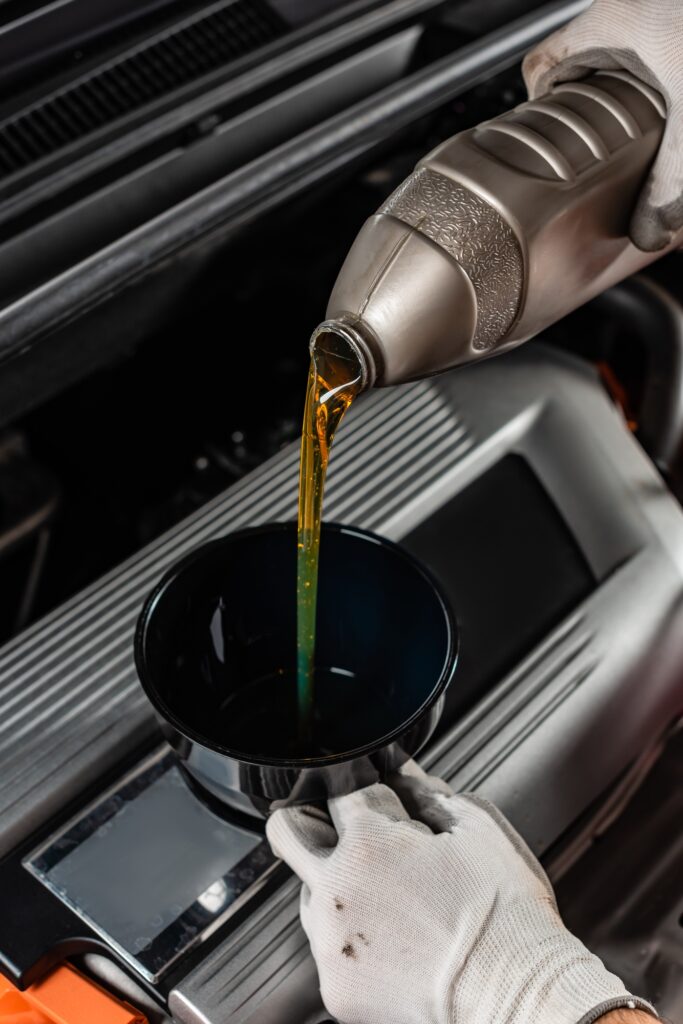 partial view of mechanic pouring machine oil at car engine